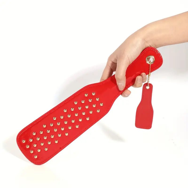 deze-glanzend-rode-paddel-is-een-leuke-instapper-voor-je-bdsm-spel-of-een-leuke-bdsm-toy-aanvulling-op-je-reeds-bestaande-assortiment-met-zijn-tientallen-vergulden-studskomt-hij-net-weer-iets-anders-aan-dan-je-andere-paddels-4