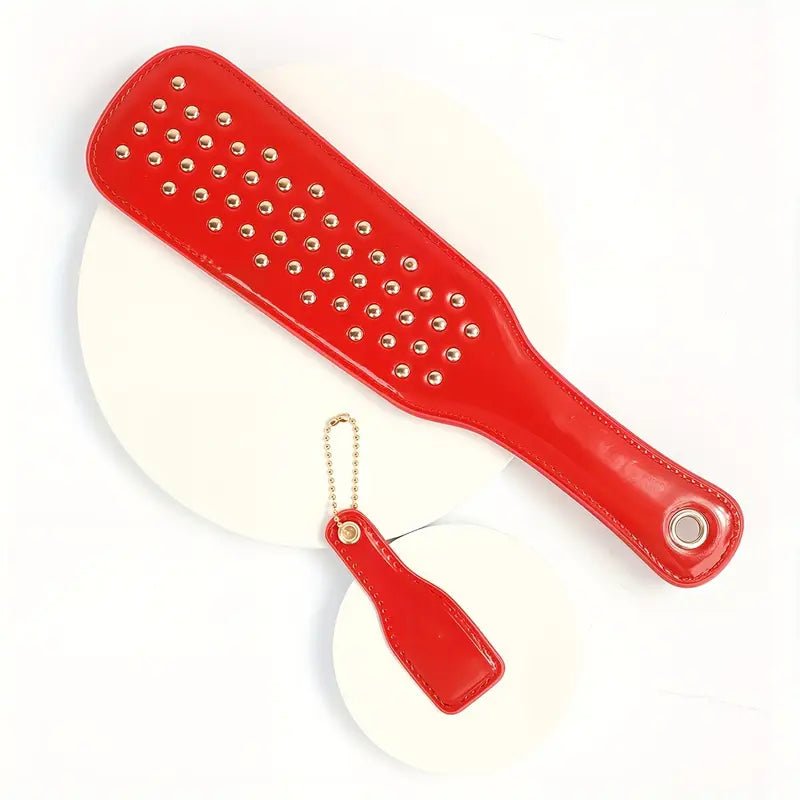 deze-glanzend-rode-paddel-is-een-leuke-instapper-voor-je-bdsm-spel-of-een-leuke-bdsm-toy-aanvulling-op-je-reeds-bestaande-assortiment-met-zijn-tientallen-vergulden-studskomt-hij-net-weer-iets-anders-aan-dan-je-andere-paddels-6